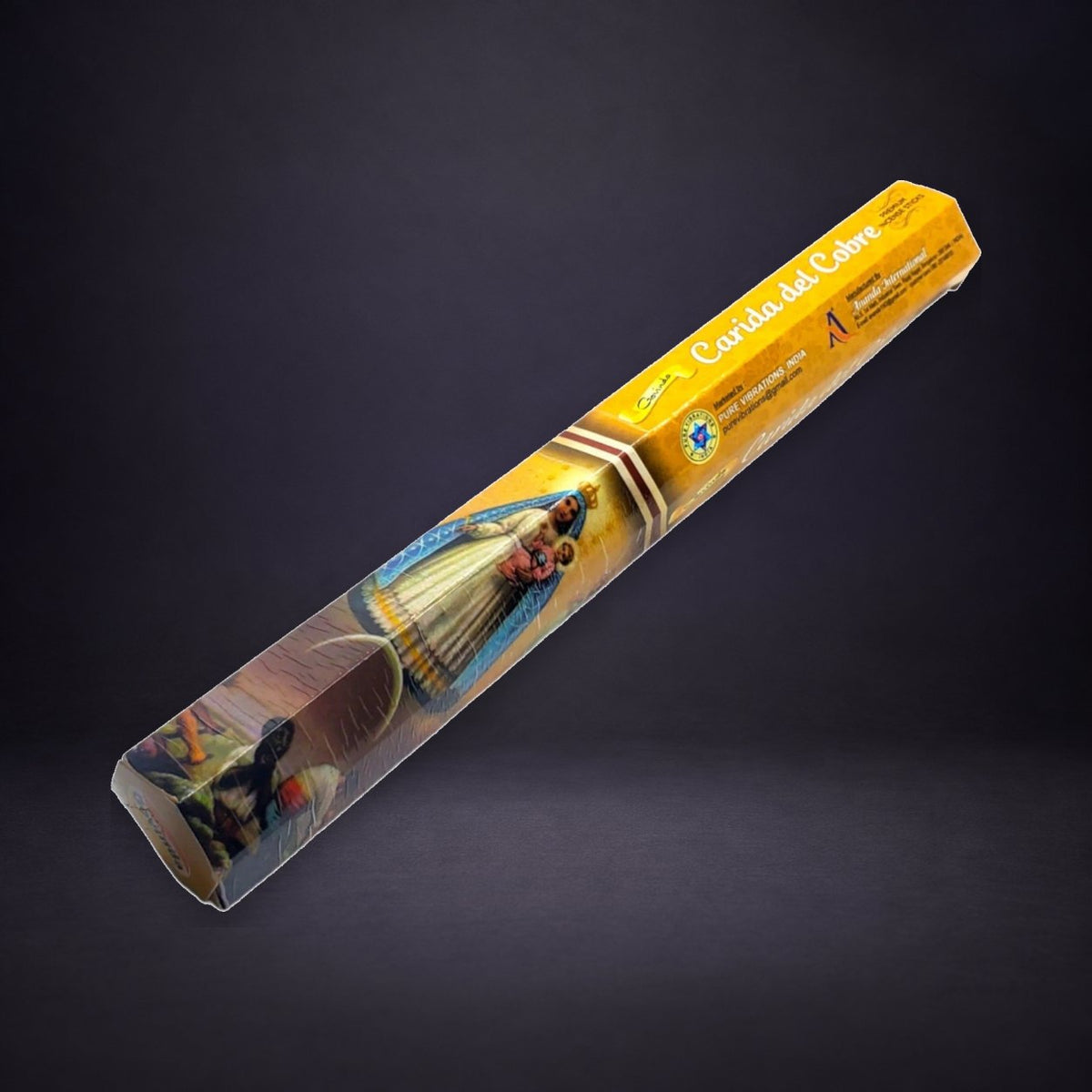 La Caridad del Cobre incense box on a matte charcoal and subtle royal-purple background.