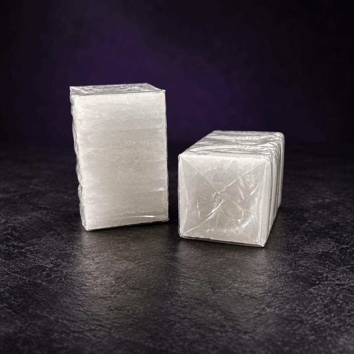 White camphor tablet blocks in clear wrapping on a charcoal and subtle purple background.