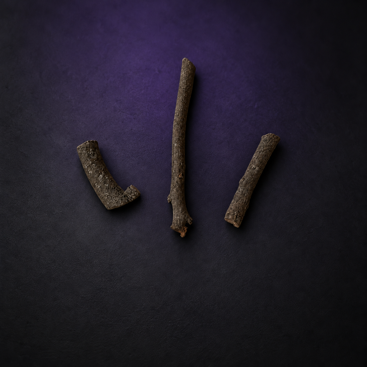 Three dry brown Dominador wood pieces on a matte charcoal and subtle purple surface.