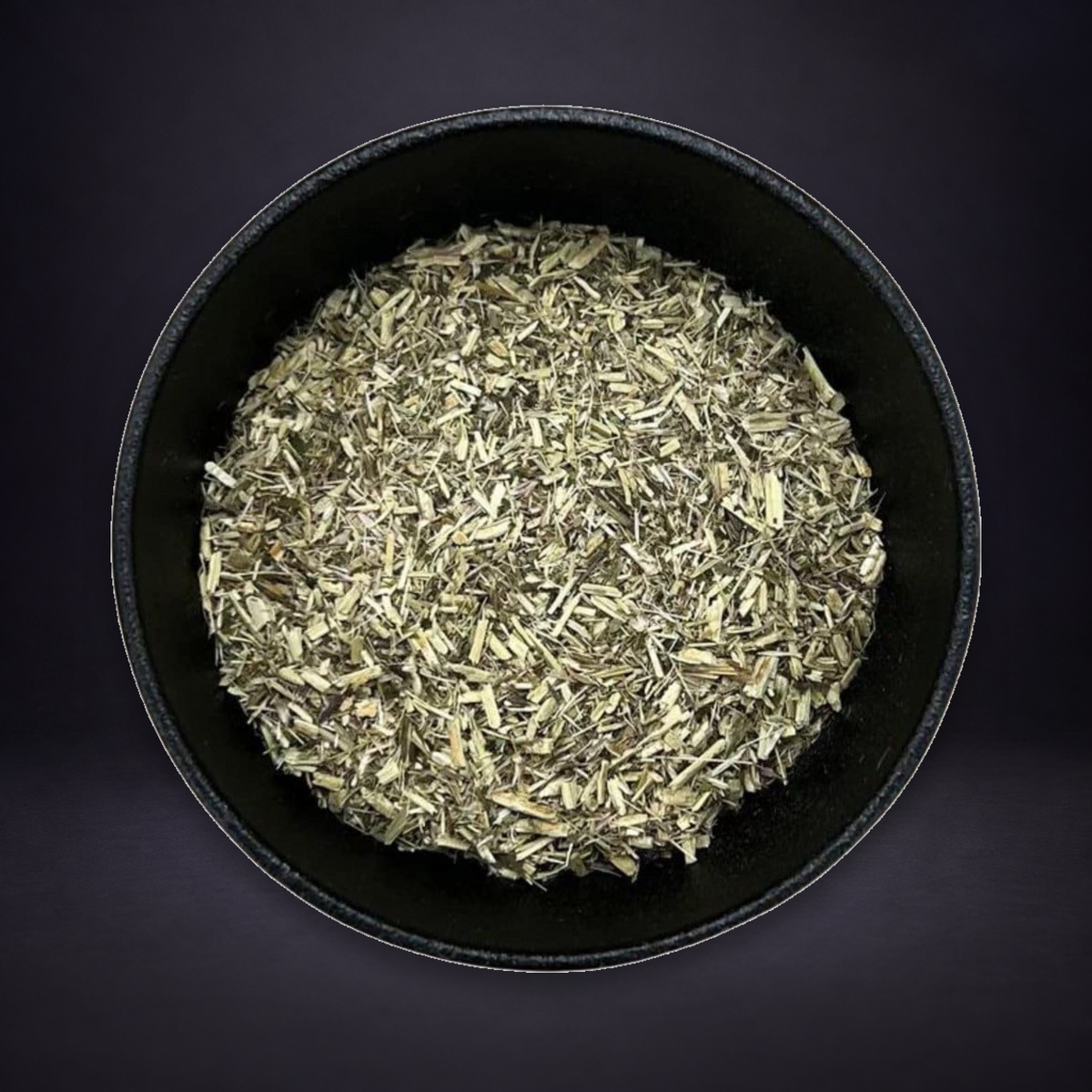 Queen of the Meadow herb in a black bowl on a matte charcoal and subtle royal-purple background.