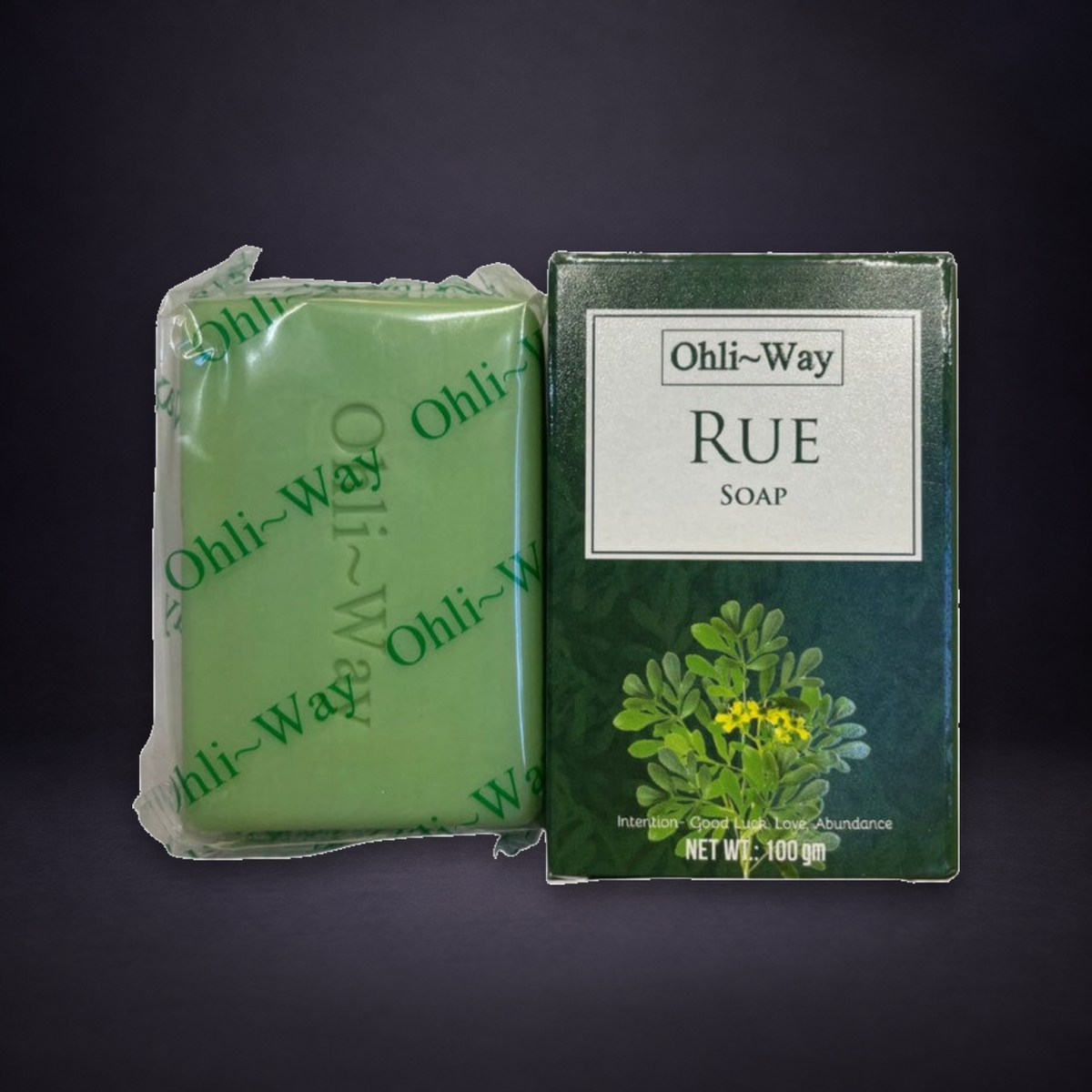 Rue Soap bar and original Ohli-Way box on a matte charcoal and subtle royal-purple background.