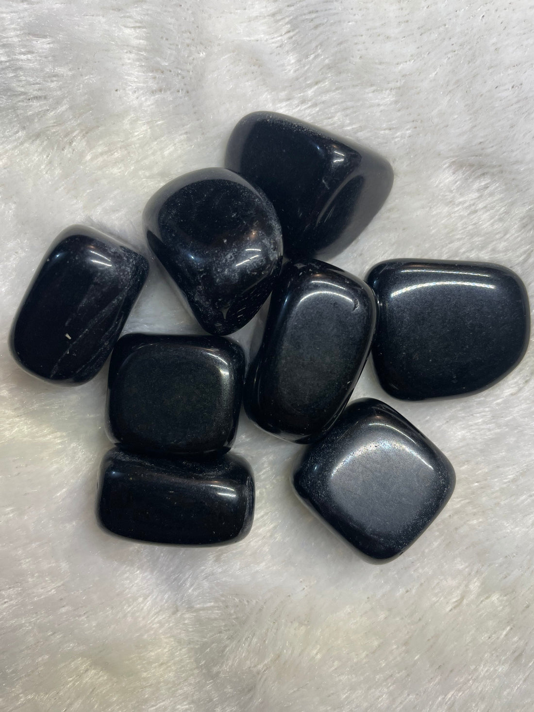 Representative polished black obsidian tumbled stones; each order includes one stone.